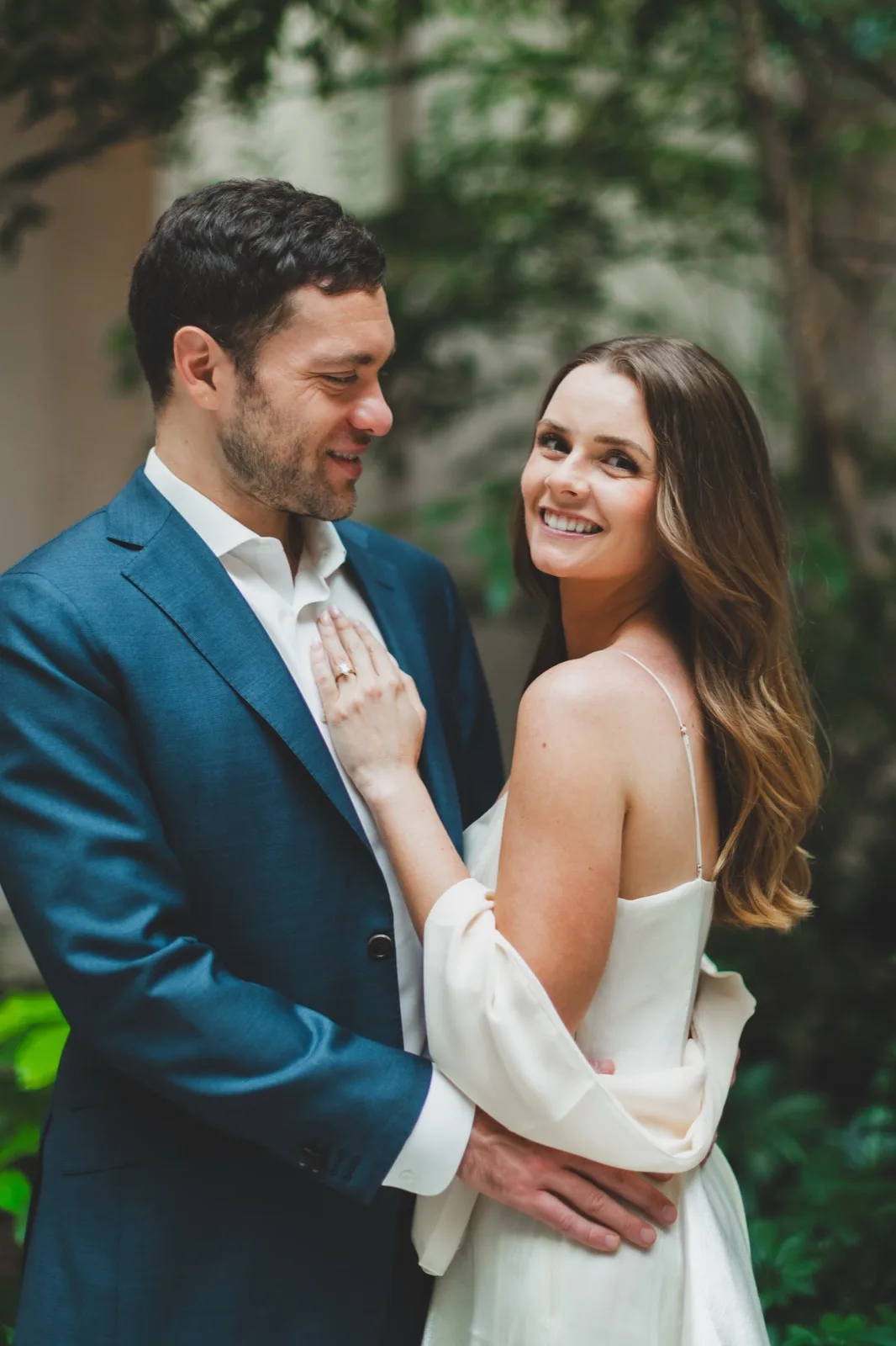 Kelsey smiling over her shoulder in the garden courtyard, held close