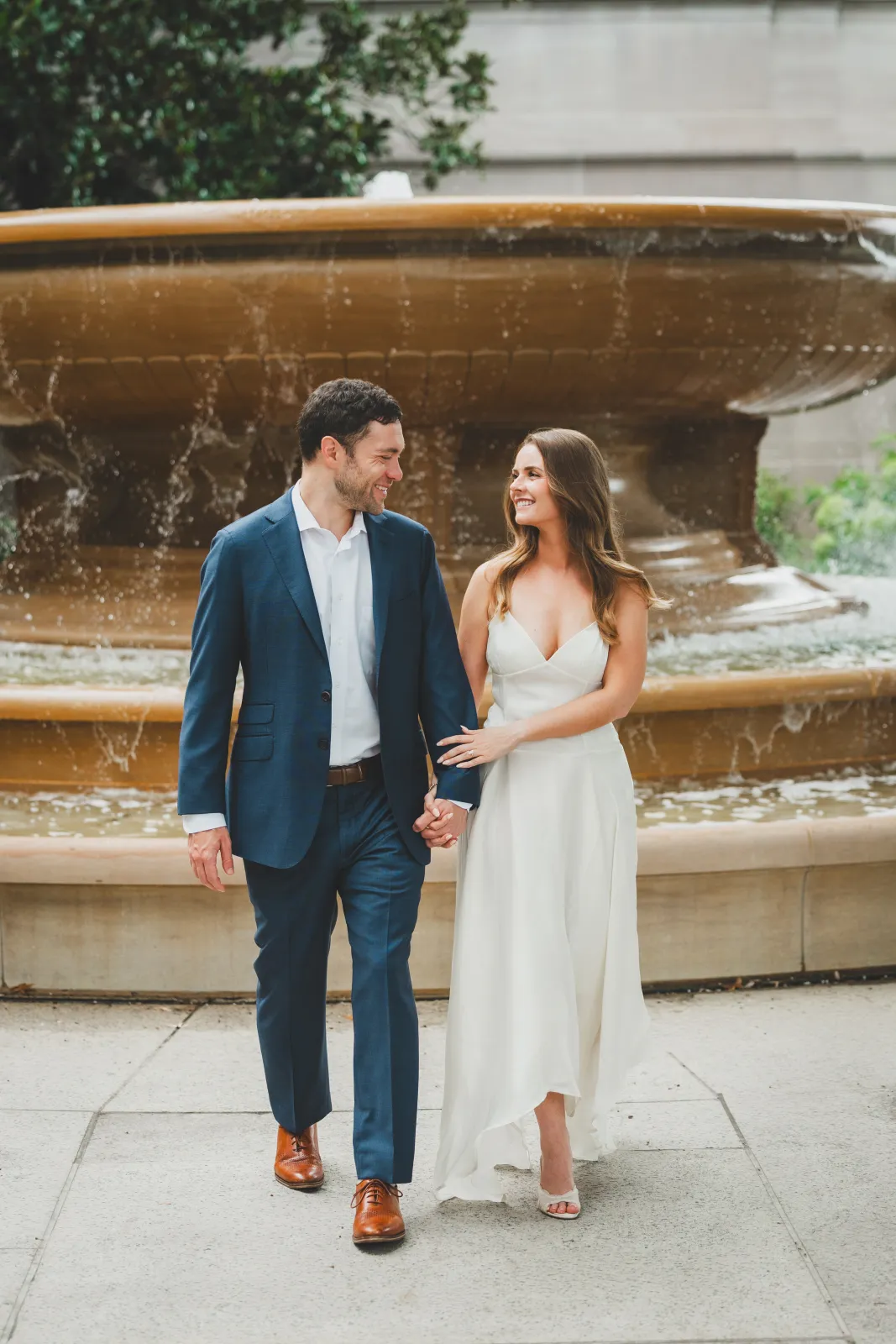 Kelsey and Shane walking hand in hand past a fountain