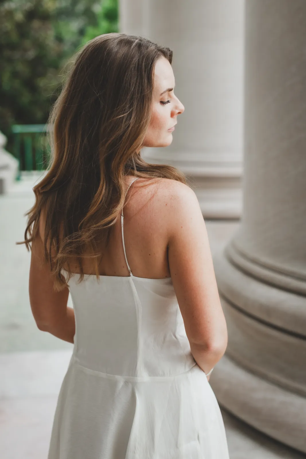 Kelsey in a white dress among stone columns