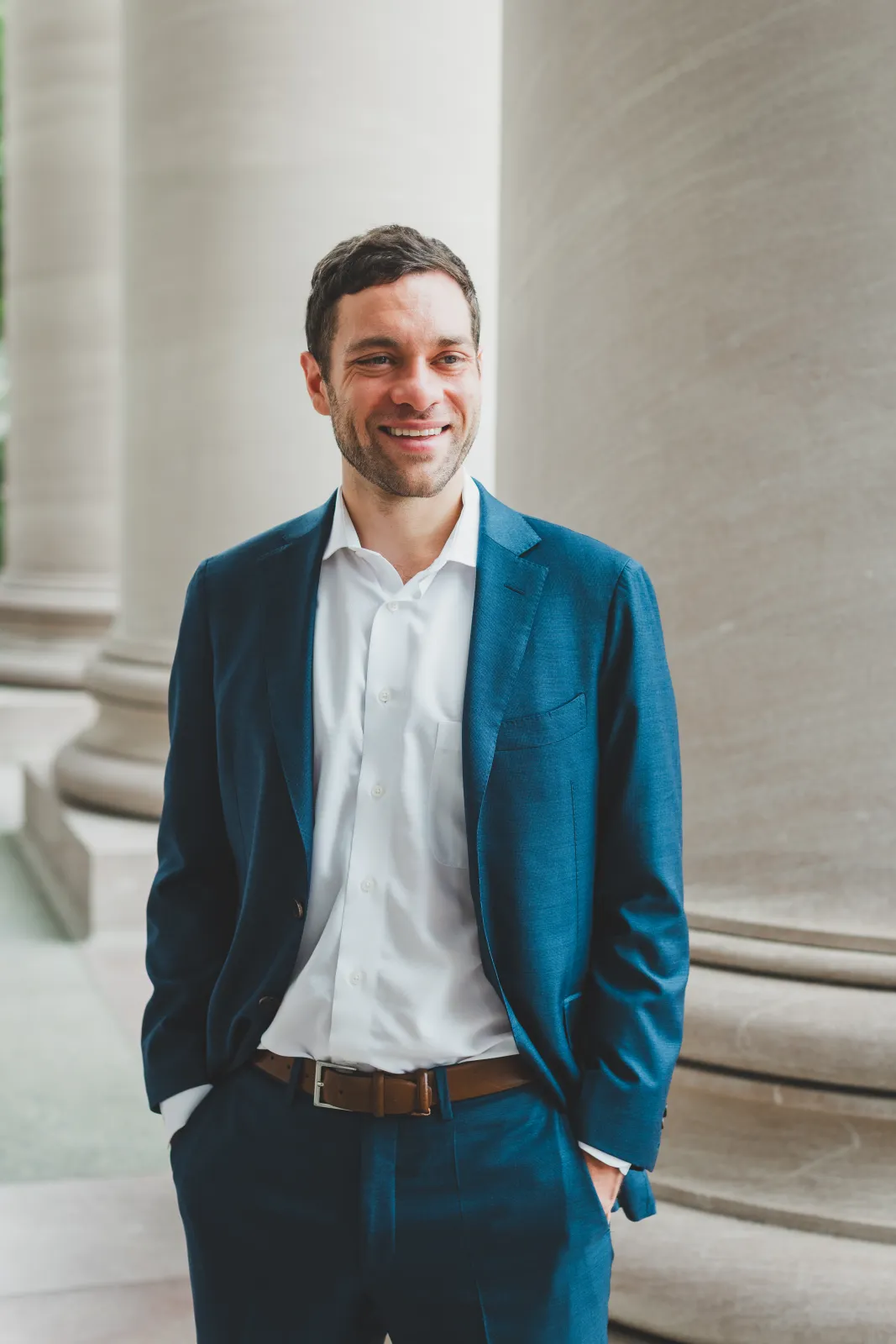 Shane in a blue suit among stone columns
